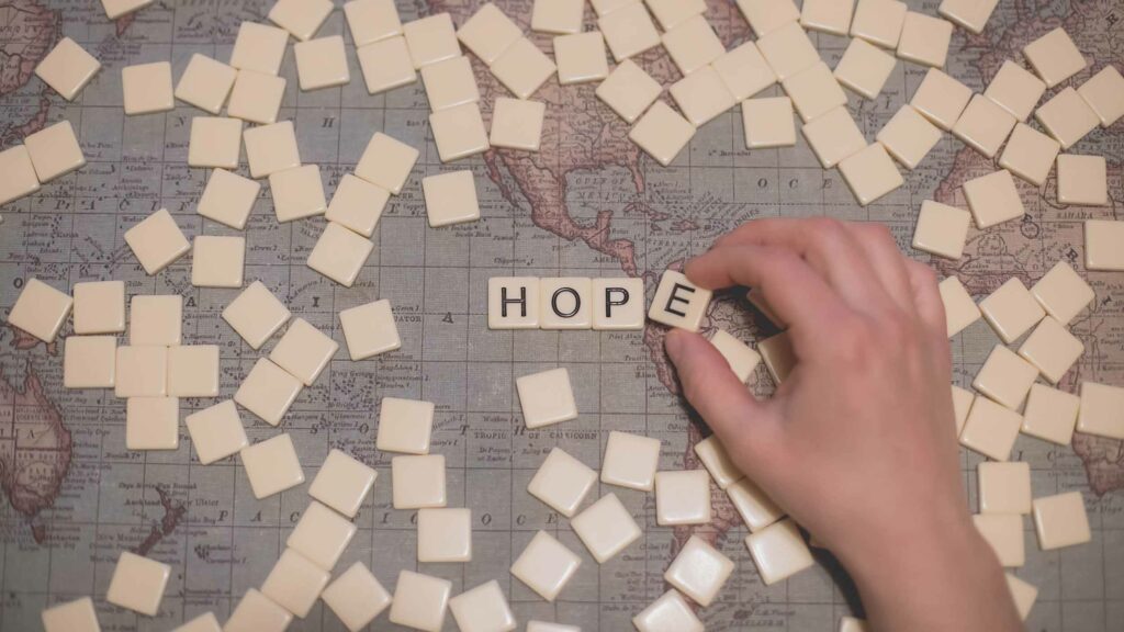 The word "HOPE" spelled with Scrabble pieces on a map